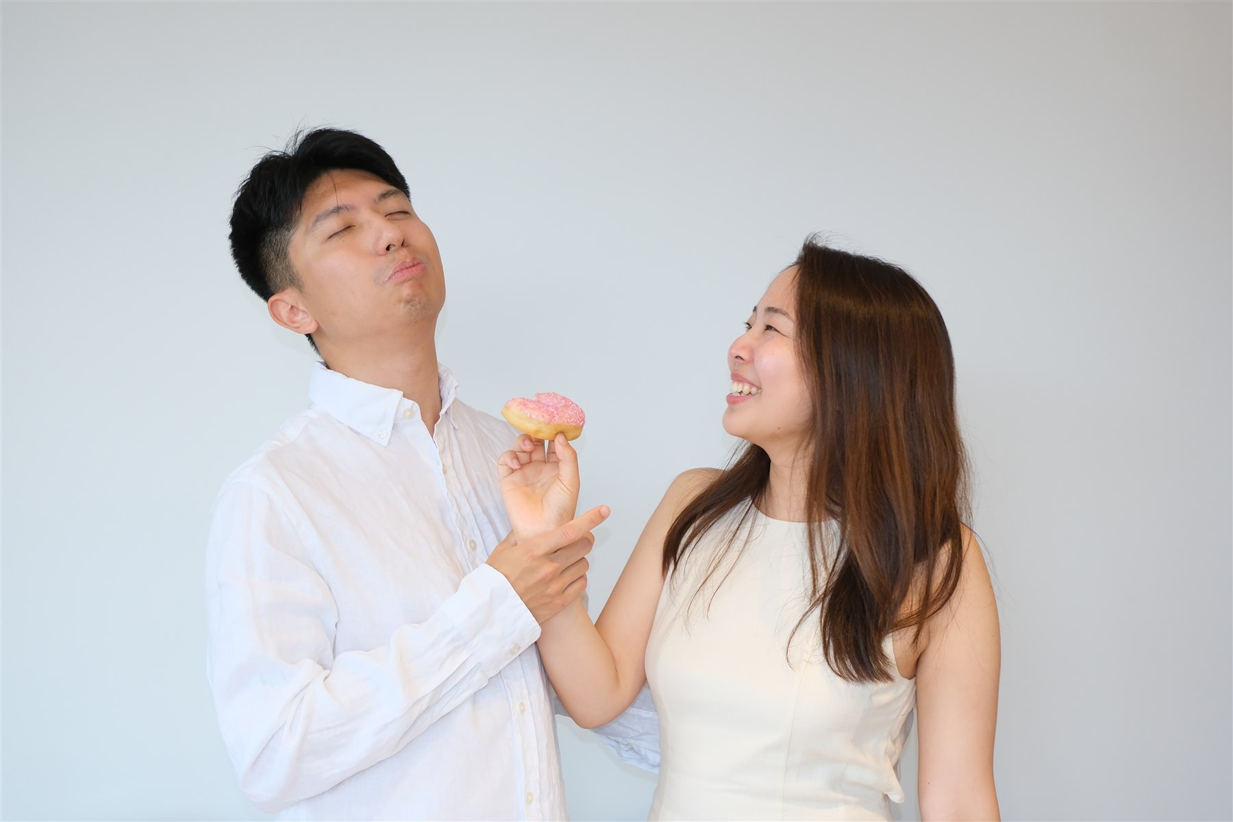 Hitomi offering Shawn a pink doughnut as they laugh
