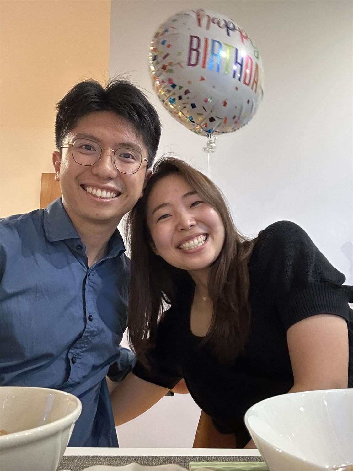 Shawn and Hitomi smiling with a birthday balloon