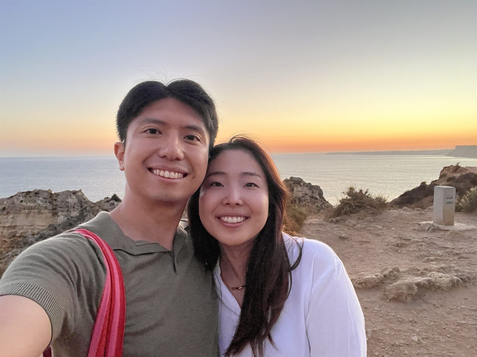Shawn and Hitomi smiling at sunset by the sea